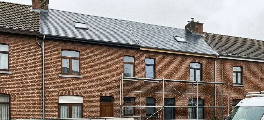 Rangée de maisons mitoyennes en briques avec toitures en ardoise et échafaudage